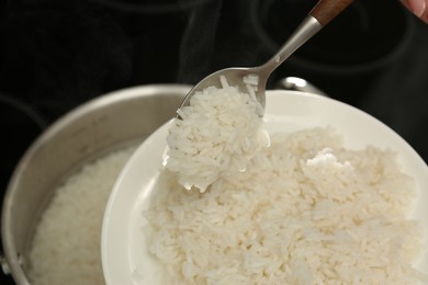 Photo of Taking boiled rice from pot into plate, closeup