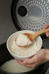 Photo of Woman taking boiled rice into bowl on grey background, closeup