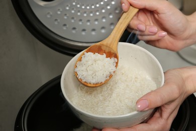 Photo of Woman taking boiled rice into bowl on grey background, closeup