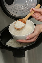 Photo of Woman taking boiled rice into bowl on grey background, closeup