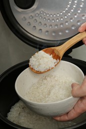 Photo of Woman taking boiled rice into bowl on grey background, closeup