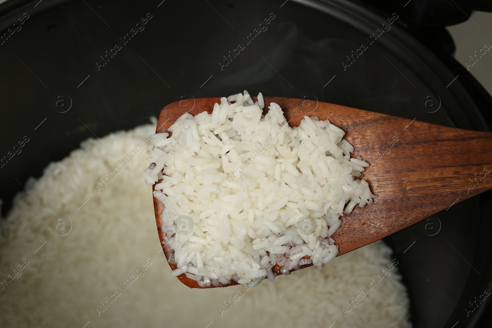 Photo of Taking boiled rice from bowl with spatula, above view