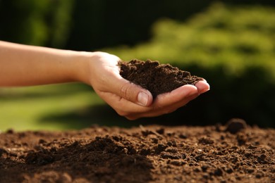 Photo of Woman holding pile of soil outdoors, closeup