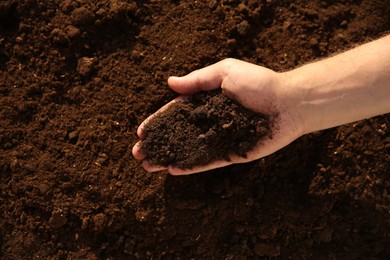 Man holding pile of soil outdoors, top view. Space for text