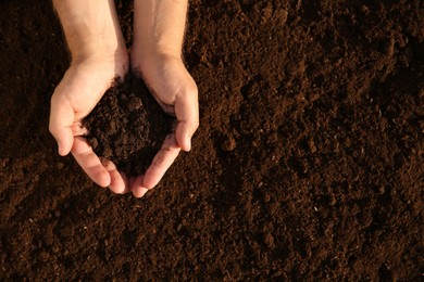 Photo of Man holding pile of soil outdoors, top view. Space for text