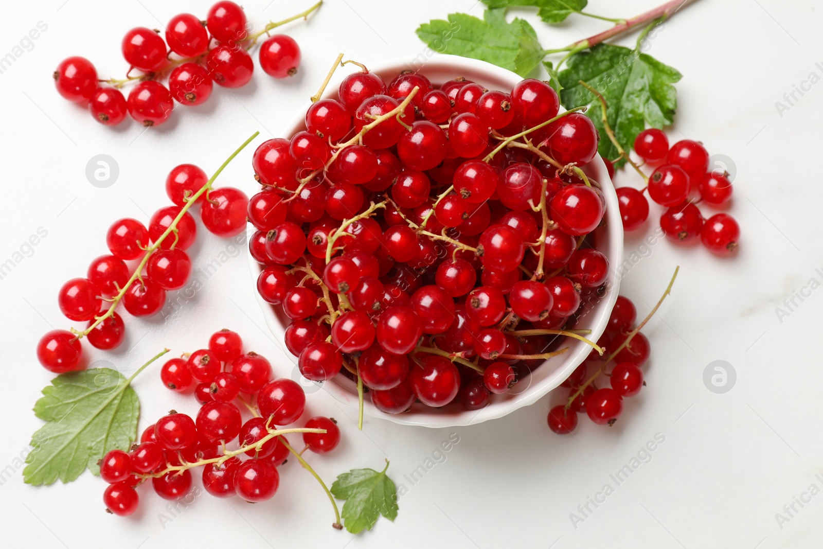 Photo of Fresh red currant berries in bowl on white table, top view