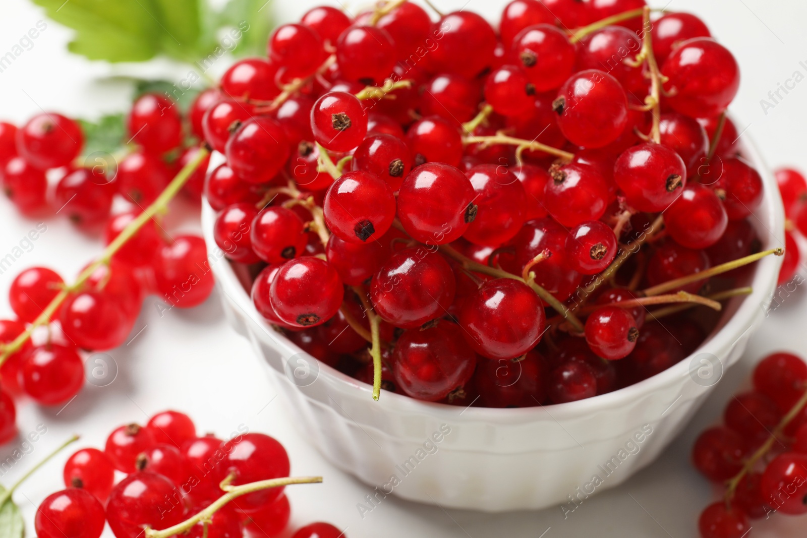 Photo of Fresh red currant berries in bowl on white table, closeup