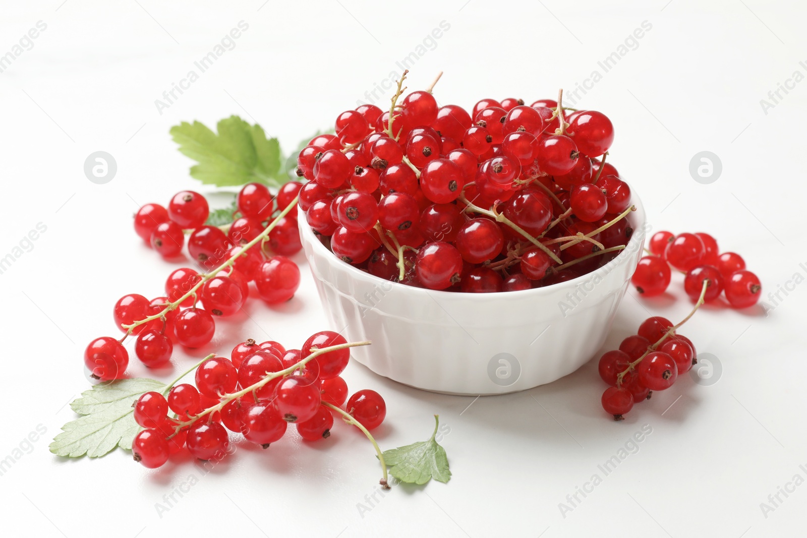 Photo of Fresh red currant berries in bowl on white table, closeup