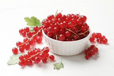 Fresh red currant berries in bowl on white table, closeup