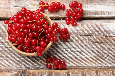 Fresh red currant berries in bowl on wooden table, top view. Space for text