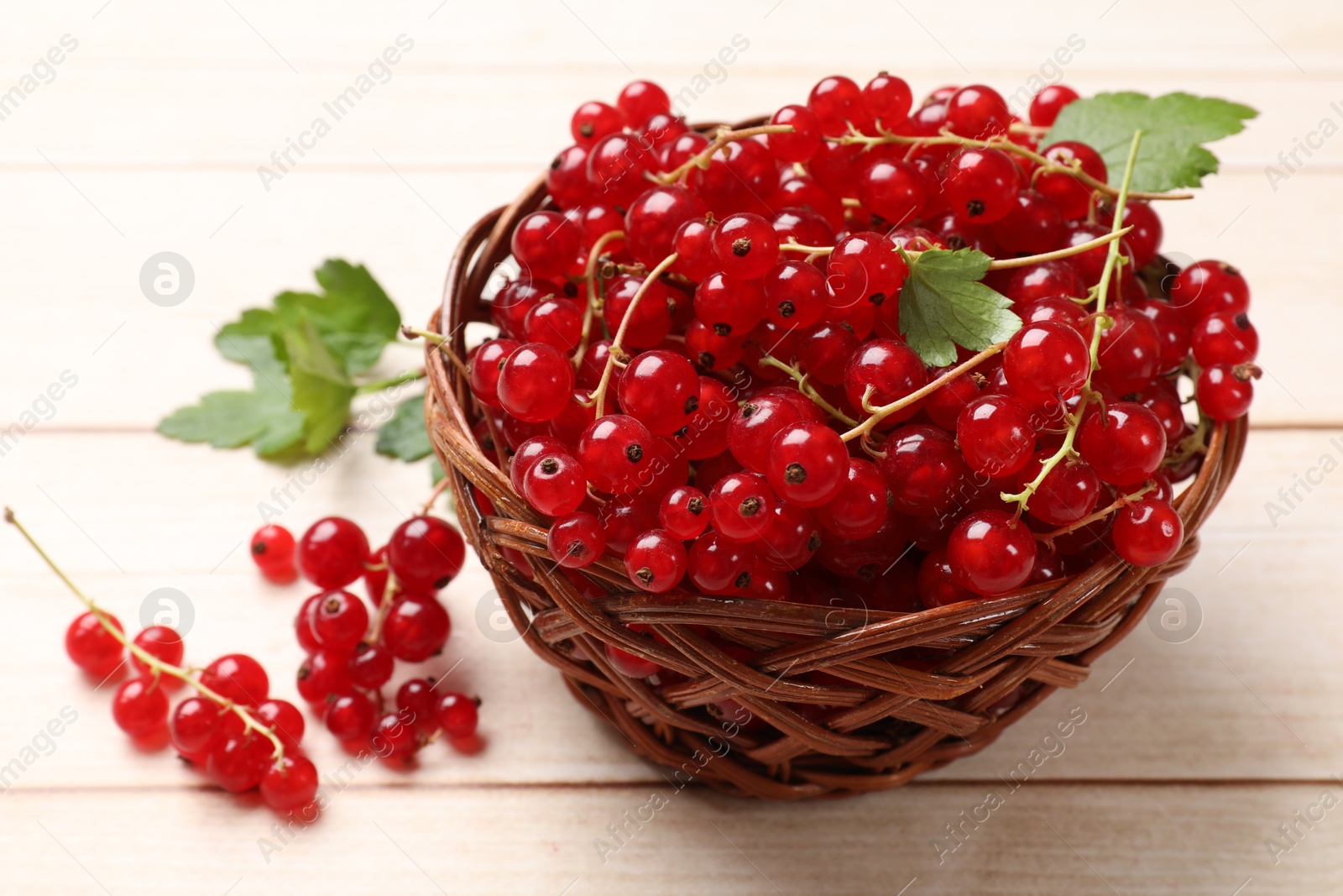 Photo of Fresh red currant berries in basket on white wooden table, closeup