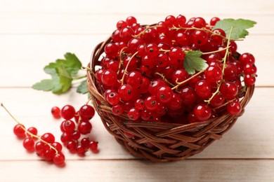 Photo of Fresh red currant berries in basket on white wooden table, closeup