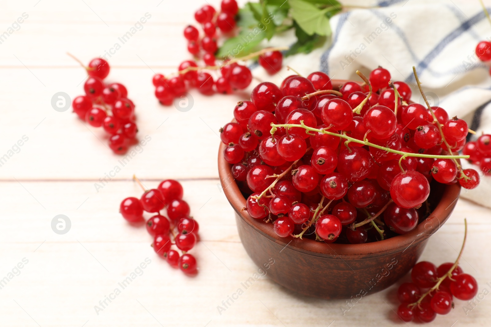 Photo of Fresh red currant berries in bowl on white wooden table, closeup