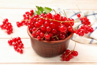 Fresh red currant berries in bowl on white wooden table, closeup