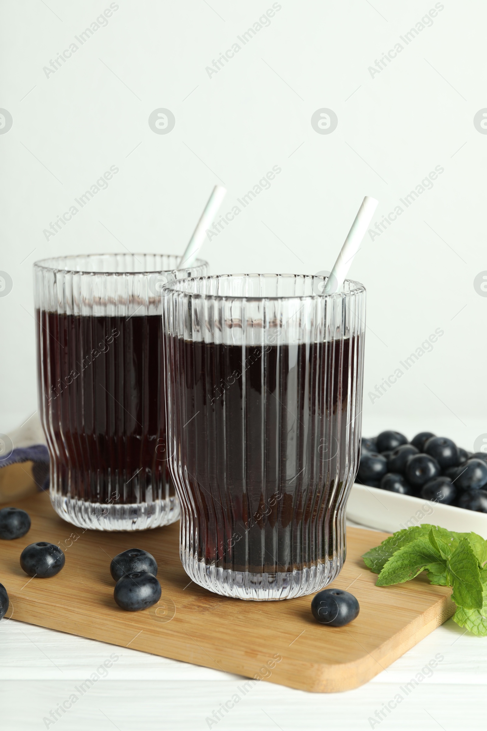 Photo of Delicious acai juice in glasses, berries and mint on white wooden table