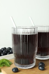 Delicious acai juice in glasses, berries and mint on white wooden table