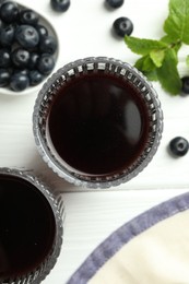 Delicious acai juice in glasses, berries and mint on white wooden table, flat lay