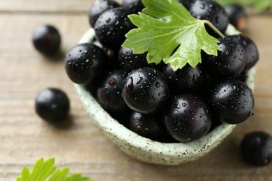 Fresh ripe black currant berries and leaves on wooden table, closeup