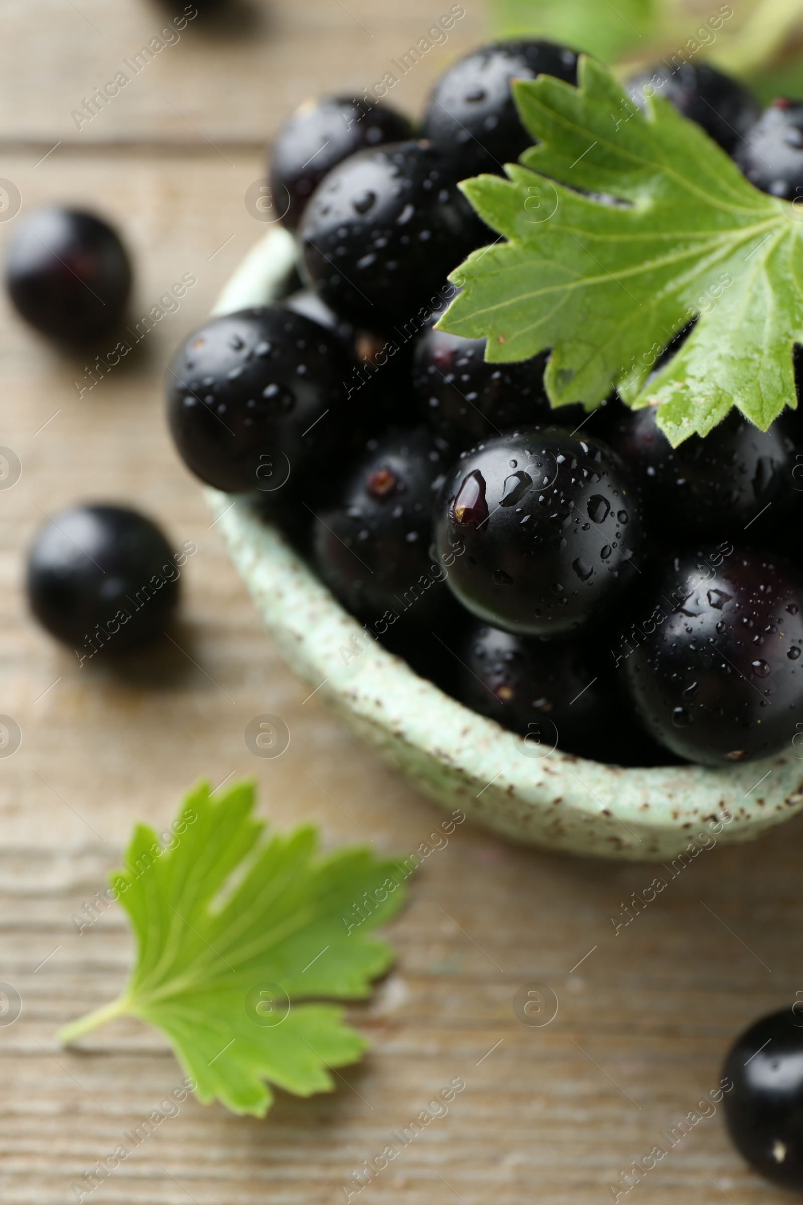 Photo of Fresh ripe black currant berries and leaves on wooden table, closeup