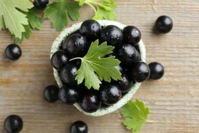 Photo of Fresh ripe black currant berries and leaves on wooden table, flat lay