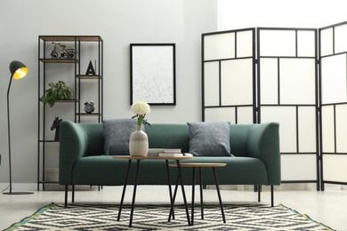 Photo of Comfortable sofa, coffee table and folding screen in stylish living room. Interior design