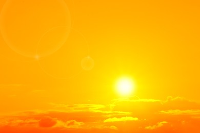 Image of Orange sky with sun and clouds during hot summer weather