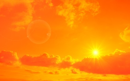 Image of Orange sky with sun and clouds during hot summer weather