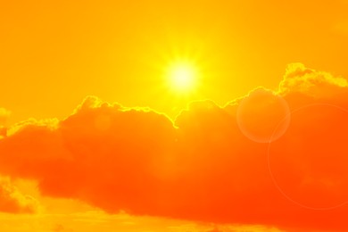 Orange sky with sun and clouds during hot summer weather