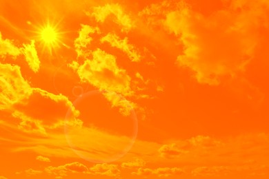 Orange sky with sun and clouds during hot summer weather