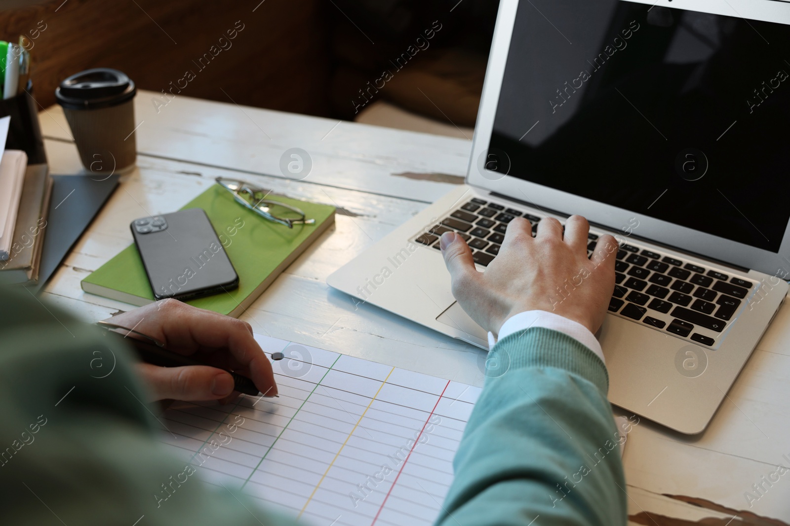 Photo of Male student with laptop studying at table in cafe, closeup