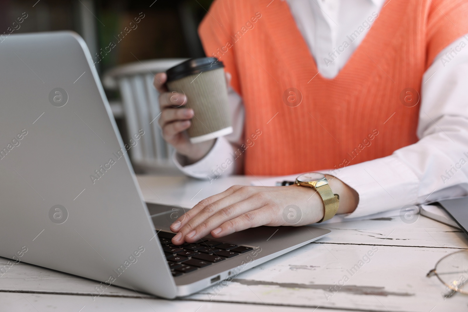 Photo of Female student with laptop and coffee studying at table in cafe, closeup