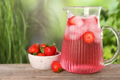 Photo of Freshly made strawberry lemonade in jug on wooden table outdoors