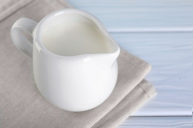 Photo of Jug of fresh milk on white wooden table, closeup