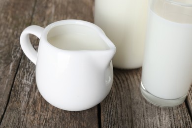 Photo of Jug of fresh milk and glass on wooden table, closeup
