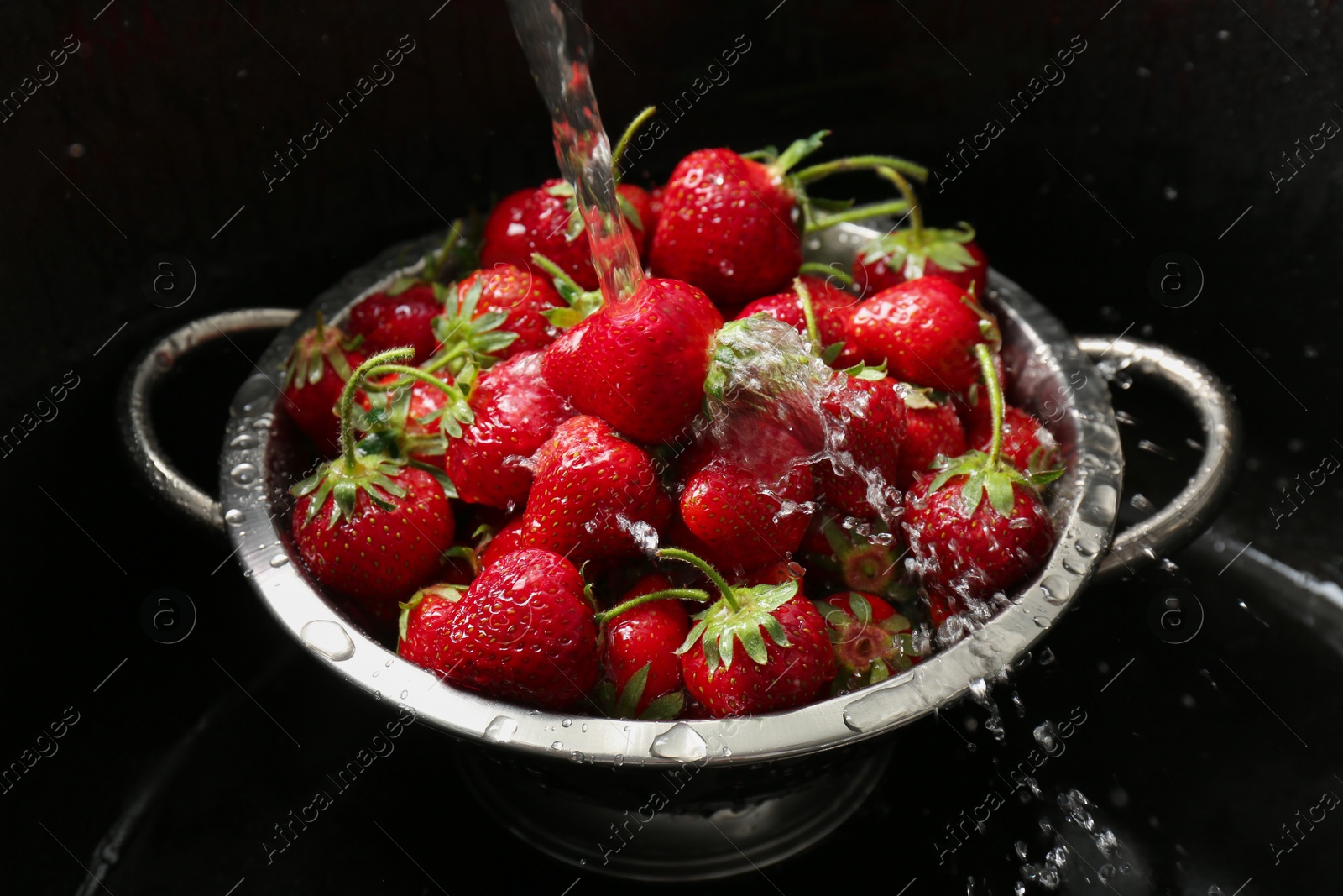 Photo of Washing fresh strawberries under tap water in metal colander in sink