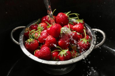 Photo of Washing fresh strawberries under tap water in metal colander in sink