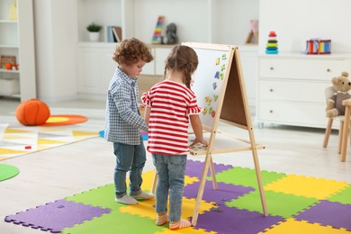 Photo of Little children learning alphabet with magnetic letters on board in kindergarten