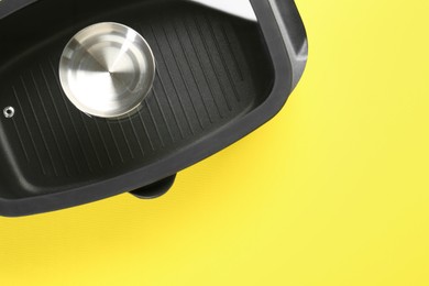 Photo of Black pot with glass lid on yellow background, top view. Space for text