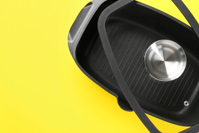 Photo of Black pot with glass lid on yellow background, top view. Space for text