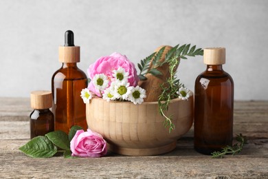 Photo of Aromatherapy. Different essential oils, flowers, mortar and pestle on wooden table