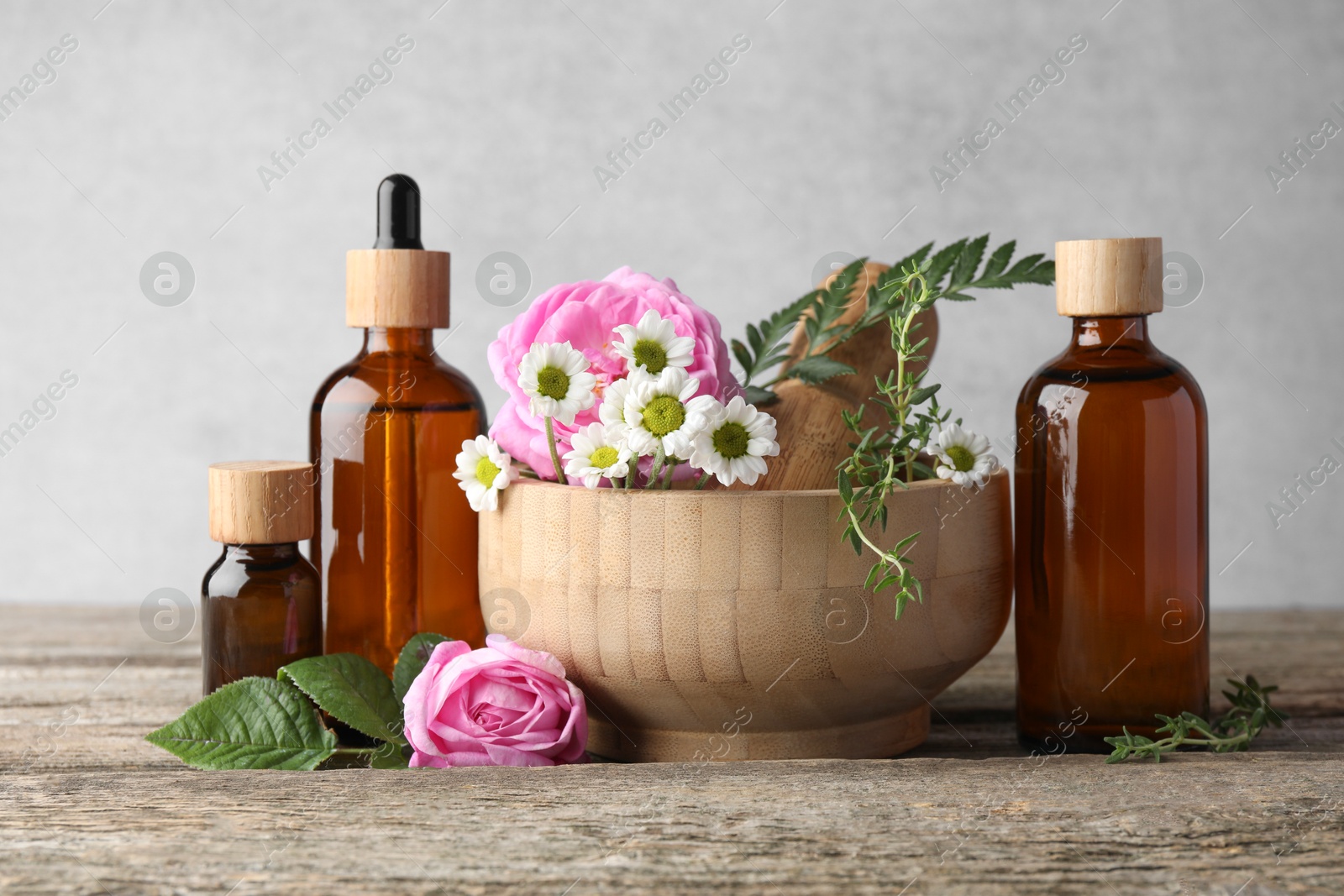 Photo of Aromatherapy. Different essential oils, flowers, mortar and pestle on wooden table