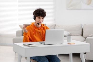 Teenager in headset having video chat via laptop at home. Remote work