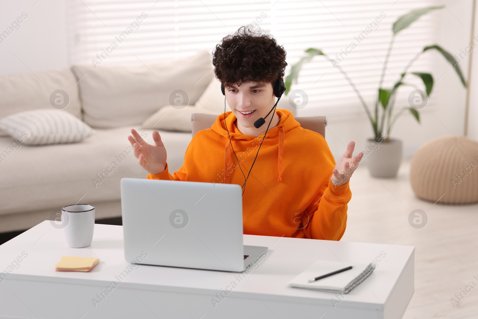 Photo of Teenager in headset having video chat via laptop at home. Remote work