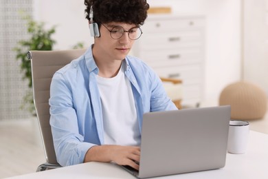 Teenager in headphones working with laptop at home. Remote job