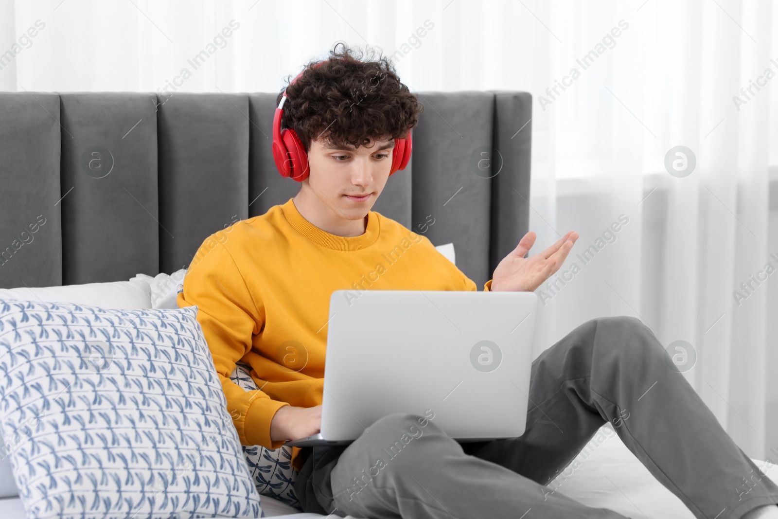 Photo of Teenager in headphones having video chat via laptop at home. Remote work