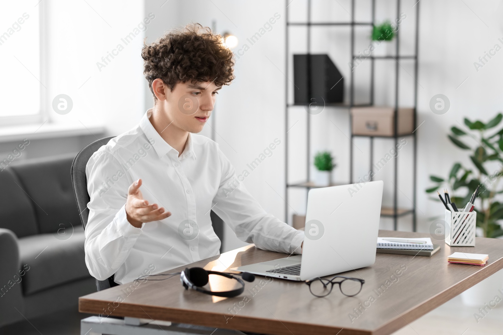 Photo of Teenager having video chat via laptop at table indoors. Remote work