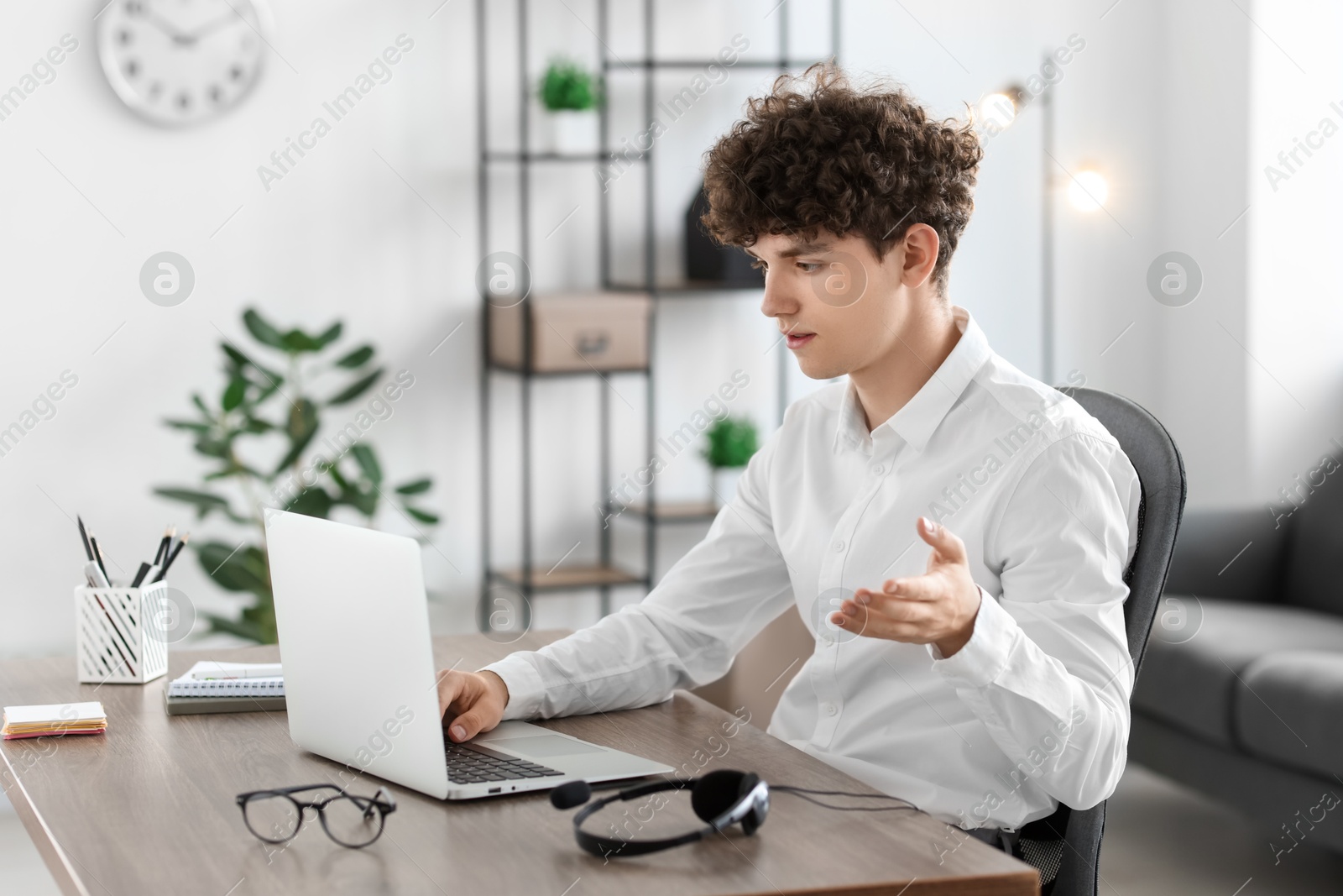 Photo of Teenager having video chat via laptop at table indoors. Remote work