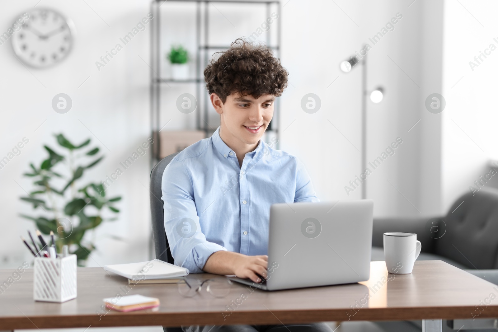 Photo of Teenager working with laptop at table indoors. Remote job