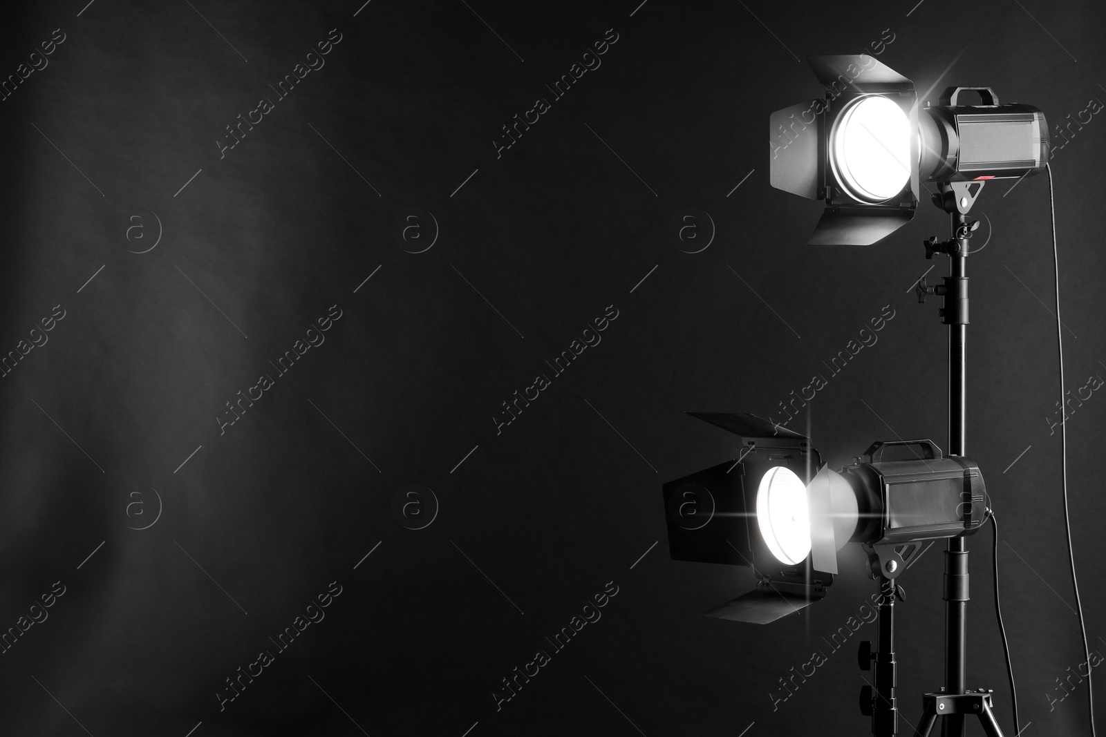 Photo of Dark photo background and professional lighting equipment in studio. Space for text