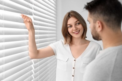 Photo of Young couple near window blinds at home